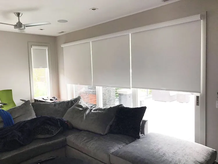 Layered roller shades across bedroom windows